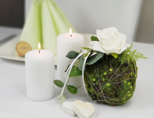 Dekorative Mooskugel mit einer Rose, Eukalyptusblättern und Farnen Dekorative Mooskugel mit einer Rose, Eukalyptusblättern und Farnen