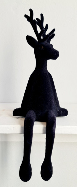 Detailaufnahme der edel beflockten Oberfläche des schwarzen Hirsch-Kantenhockers vor festlichem Hintergrund.